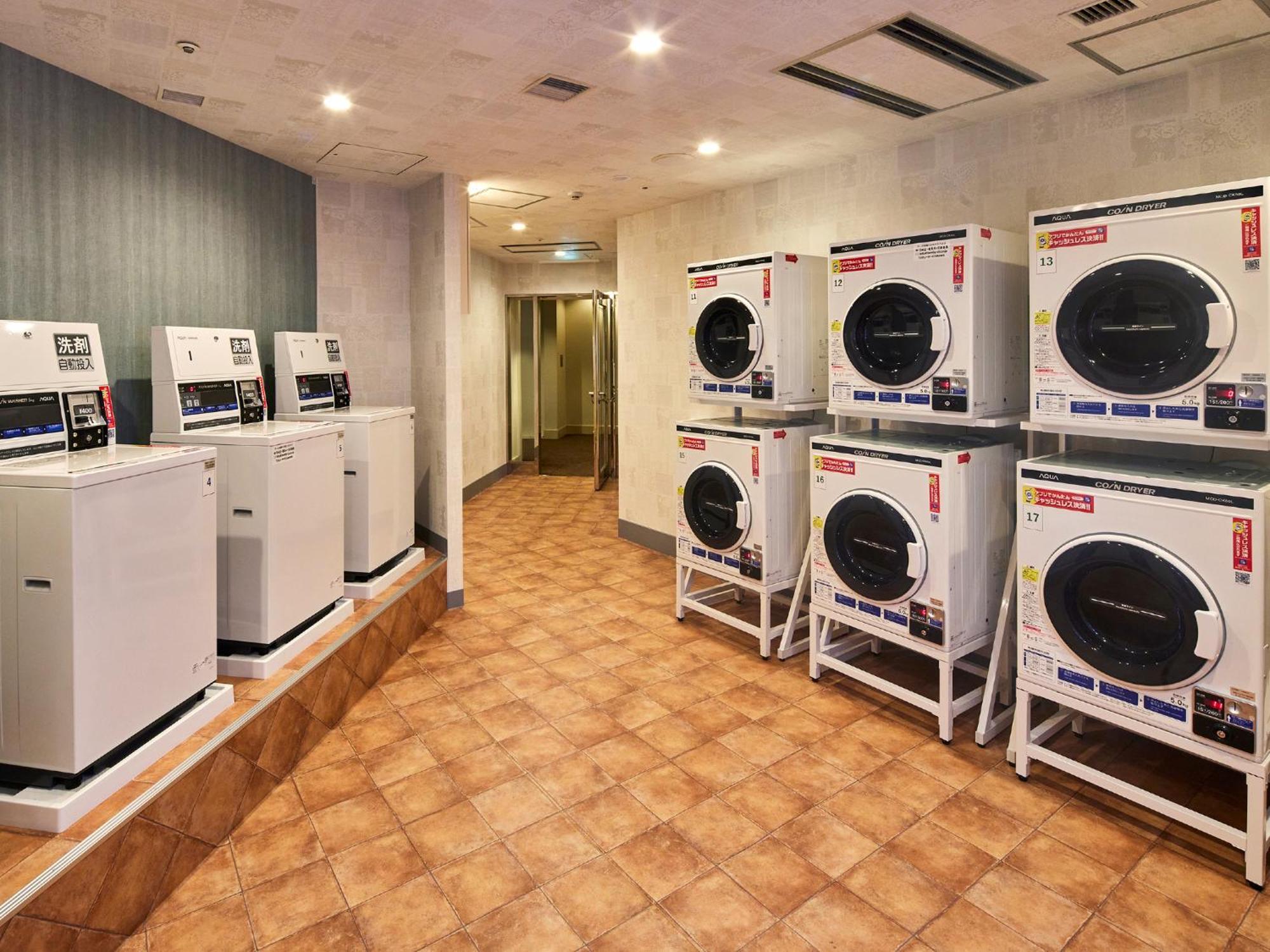 แกรนด์ นิกโกะ โตเกียว เบย์ ไมฮามะ Hotel Urayasu ภายนอก รูปภาพ The photo shows a laundry room with several washing machines and dryers. On the left side, there are five white washing machines, and on the right side, there are four dryers. The machines are arranged in a clean, tiled space with a neutral-colored w